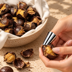Stainless steel finger guard used to peel a roasted chestnut beside a cloth-lined bowl of chestnuts